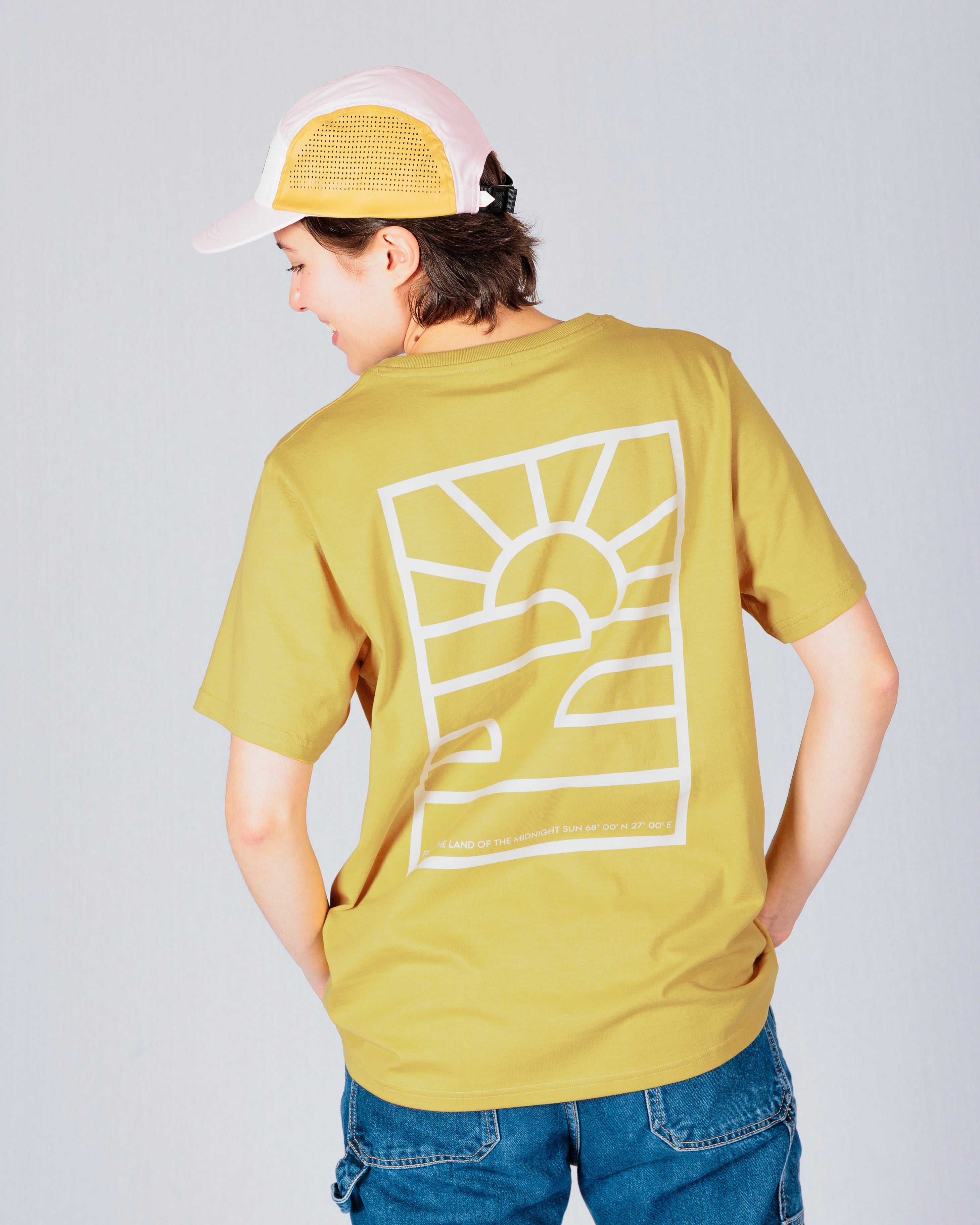 Person in yellow t-shirt with sun graphic and jeans, wearing a pink cap, facing away from the camera.