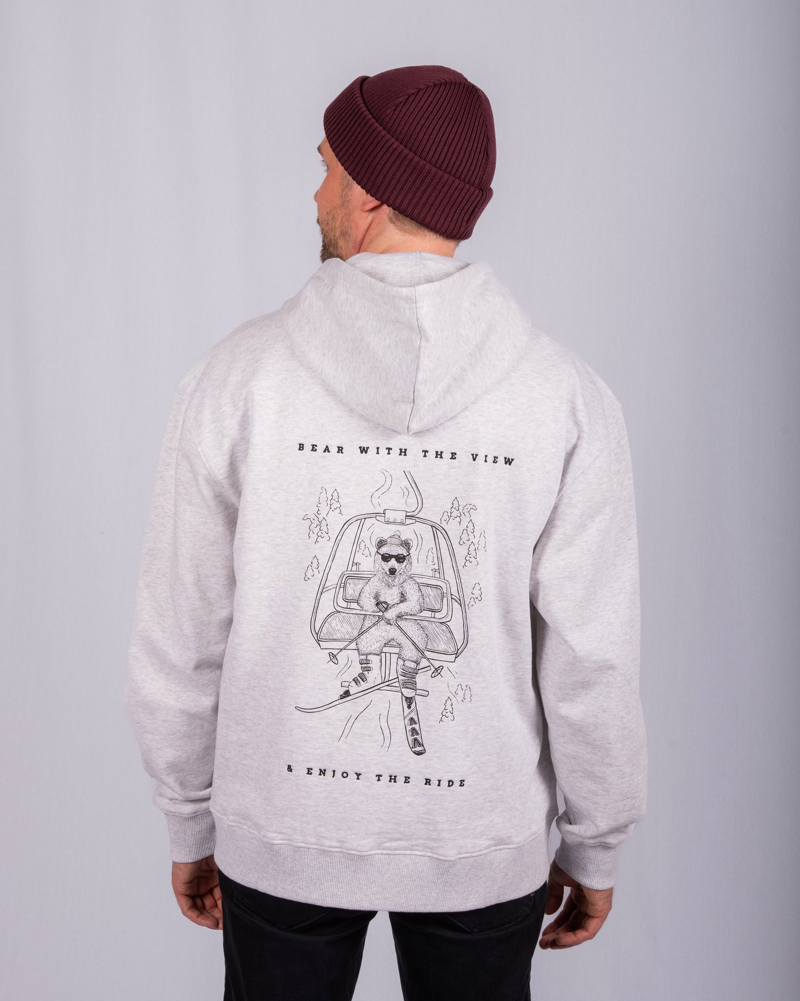 Man in gray hoodie and maroon beanie, showing bear graphic and text Bear with the view & enjoy the ride..