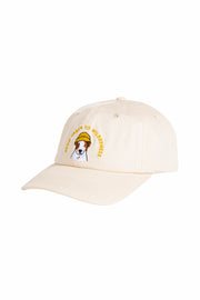 Beige baseball cap with an embroidered dog wearing sunglasses and text that reads TOO URBAN TO WILDERNESS.