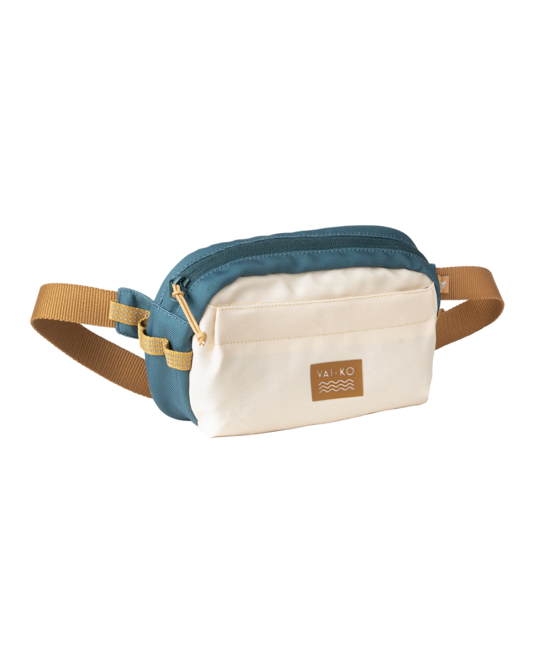 A canvas belt bag with teal sides, cream front, tan strap, and a brown Vai-Ko logo patch.