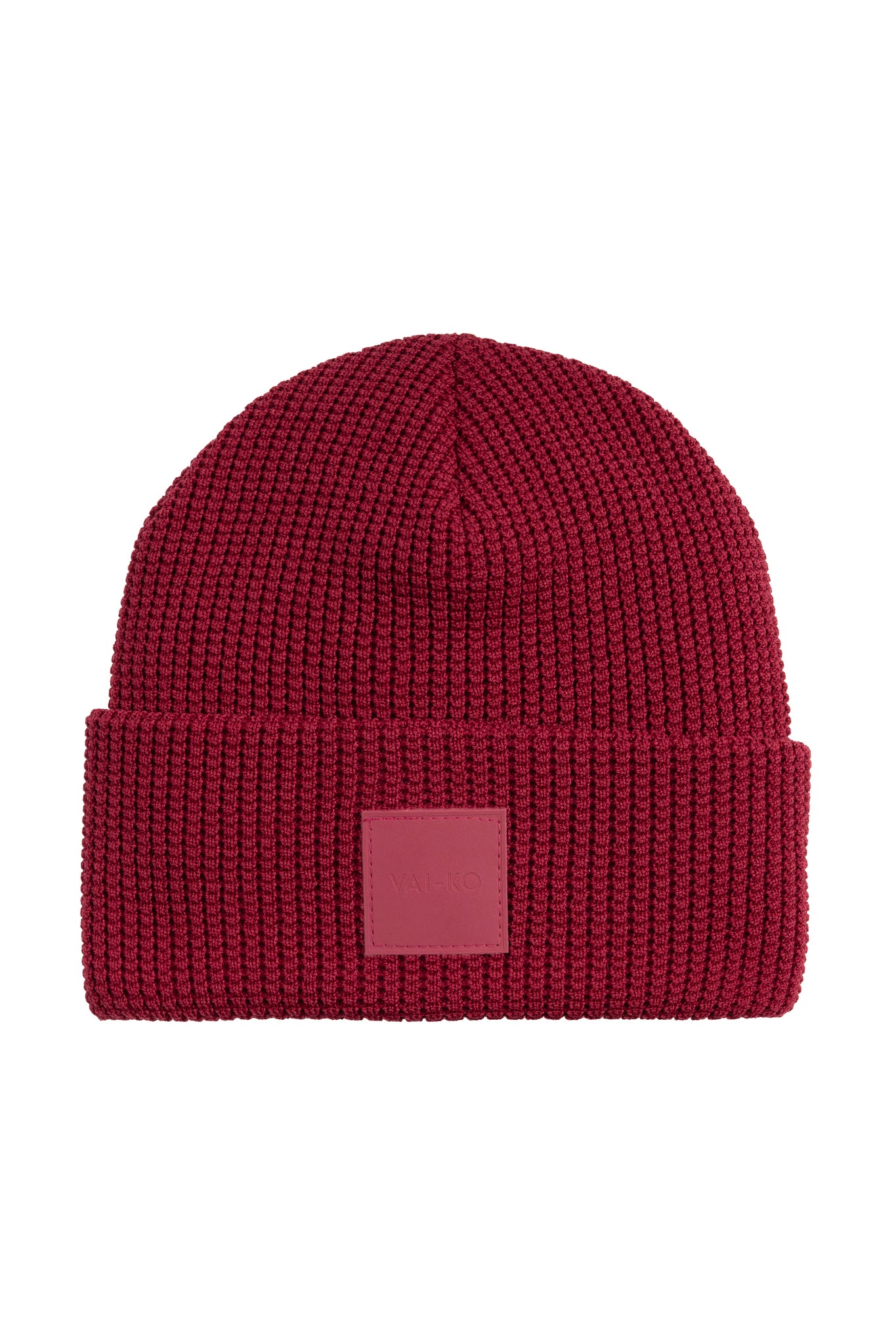 Dark red ribbed knit beanie with a folded cuff and a square patch on the front.