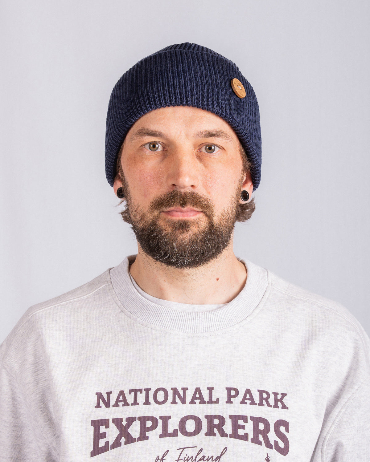 Man with a beard wearing a navy knit beanie and a gray National Park Explorers sweatshirt.